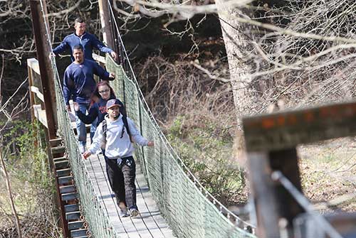 STudents cross suspension bridge during an orientation day hike